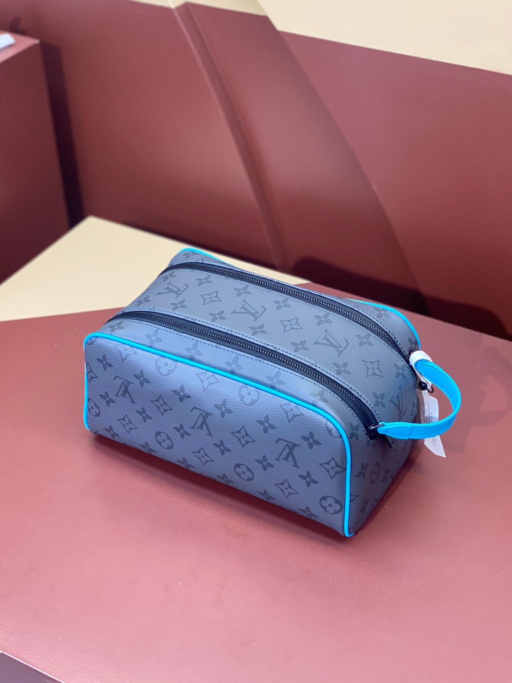 Louis Vuitton toiletry bag with monogram print and blue piping, side view with strap