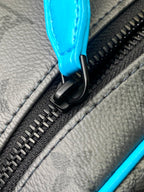 Louis Vuitton zipper pull close-up with black hardware and bright blue leather tab