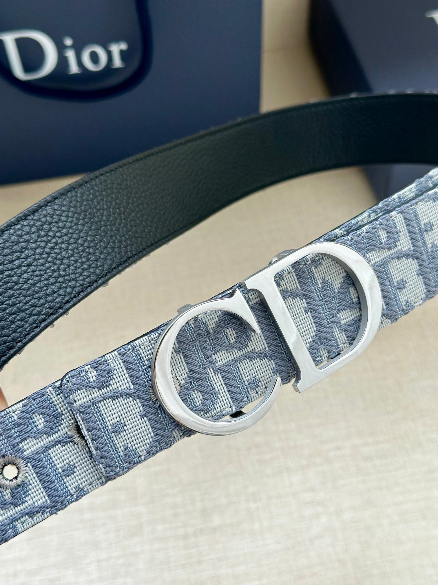Dior belt close-up with silver double CD buckle on light-blue logo strap