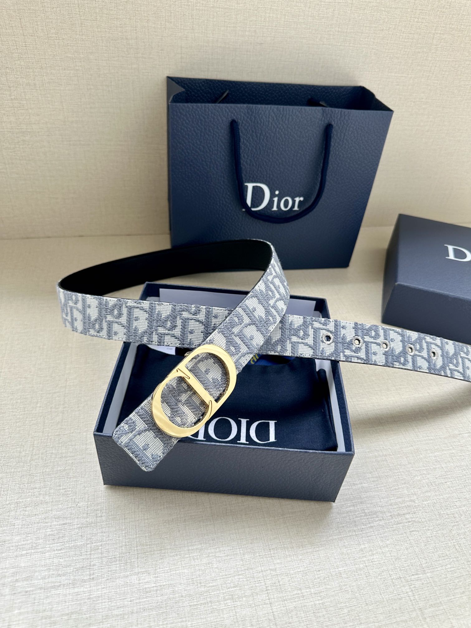 Dior belt with light blue-gray monogram strap and gold-tone D-shaped buckle