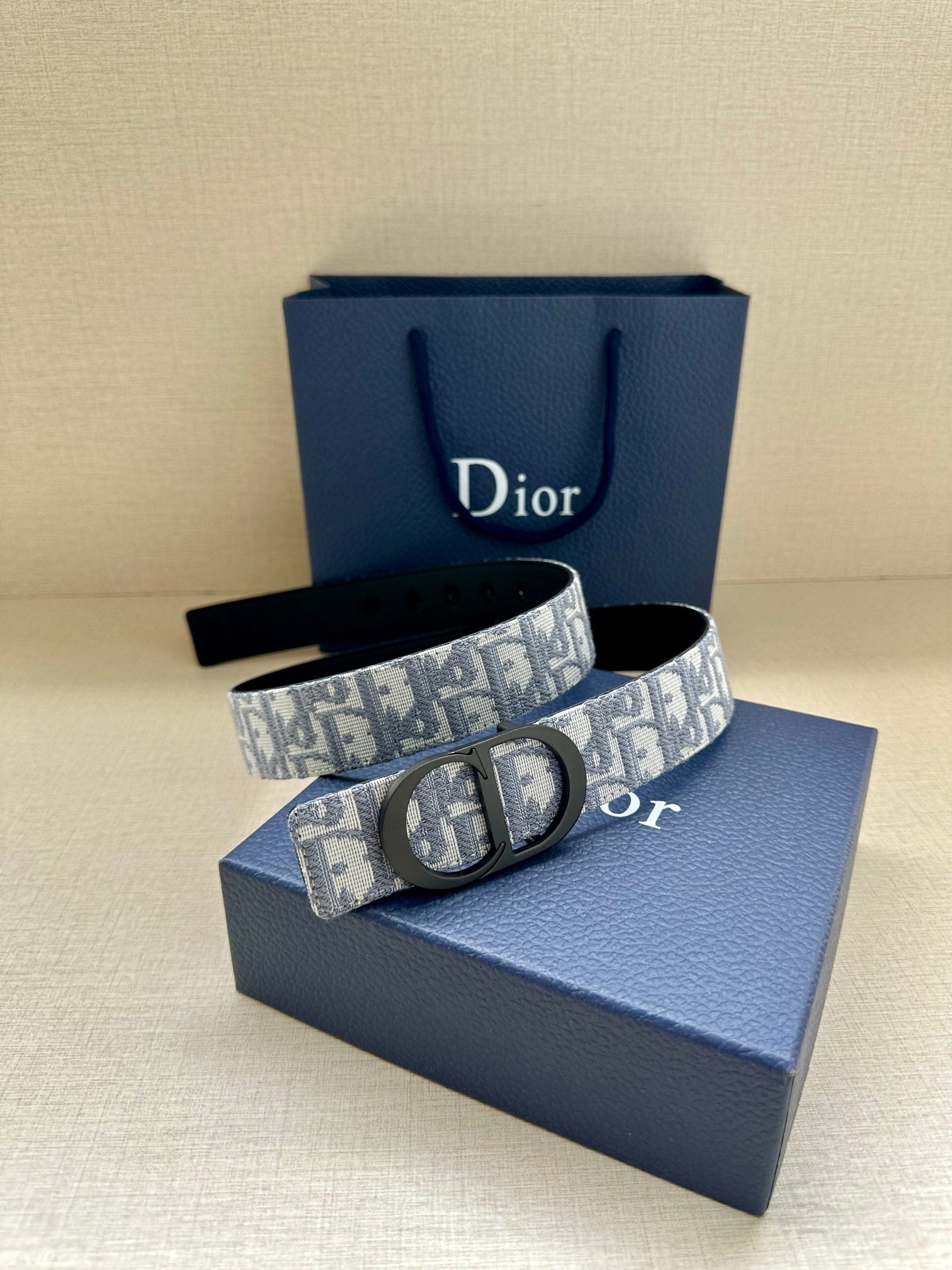 Monogram belt with oval buckle, blue-and-gray patterned strap on gift box
