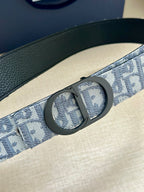 Monogram belt buckle detail on blue-gray patterned strap with leather edge