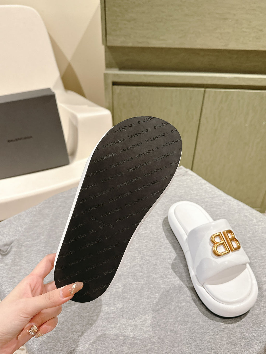 Balenciaga slide sandal outsole with dark tread; white upper with gold “BB”