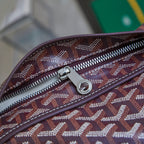 Goyard patterned zipper on burgundy top-handle bag with metal pull and teeth.