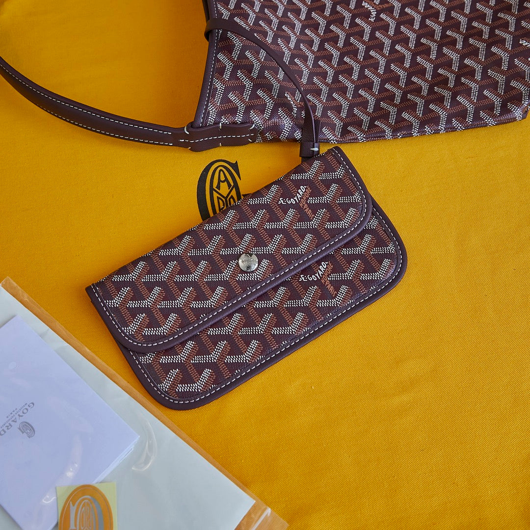Burgundy patterned Goyard mini pouch wallet with flap and wrist strap.