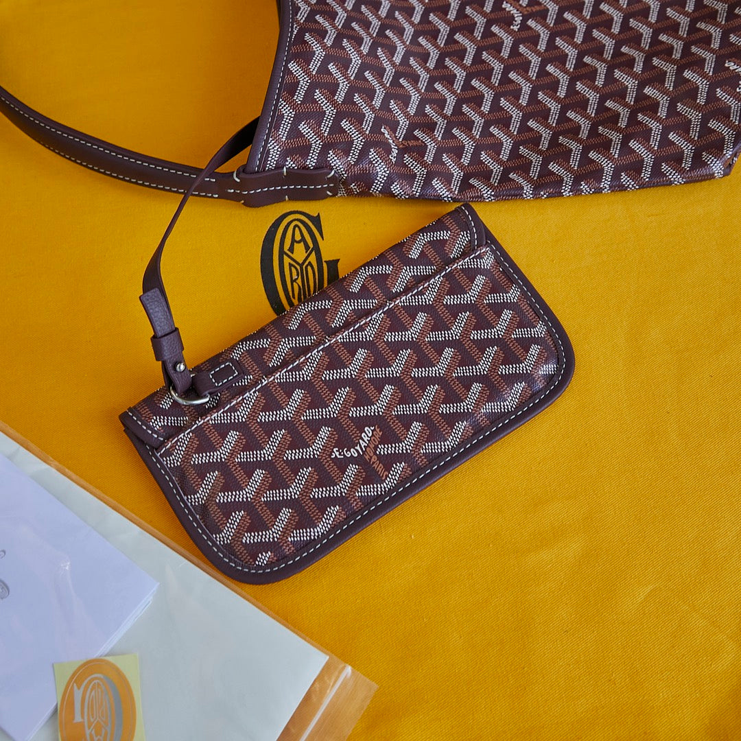 Burgundy patterned Goyard mini pouch wallet with shoulder strap and gold emblem.