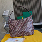 Burgundy patterned Goyard tote bag with top handles and green lining visible.