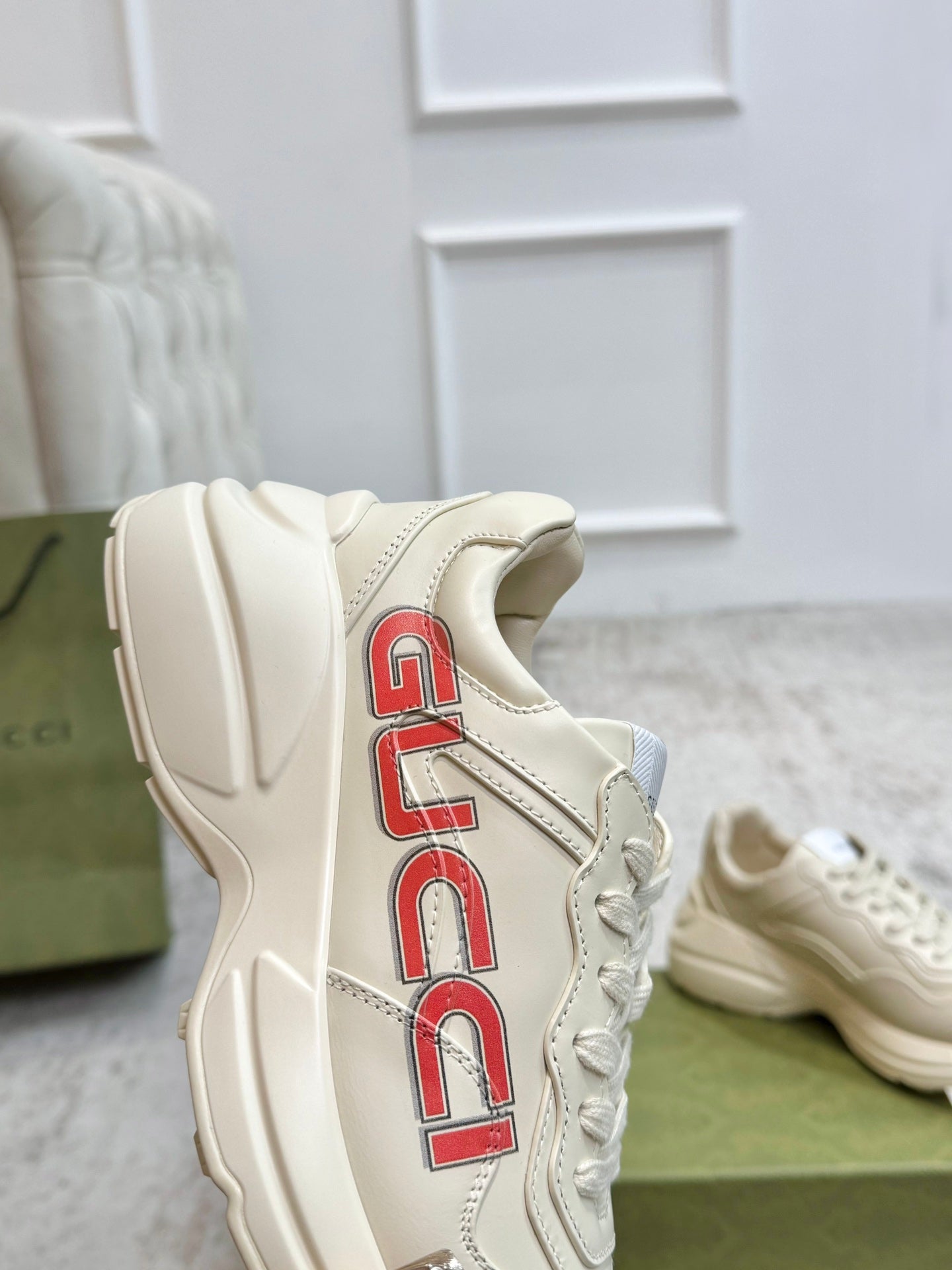 Cream Gucci unisex sneakers with red GUCCI vertical logo on side and mesh lace panel.