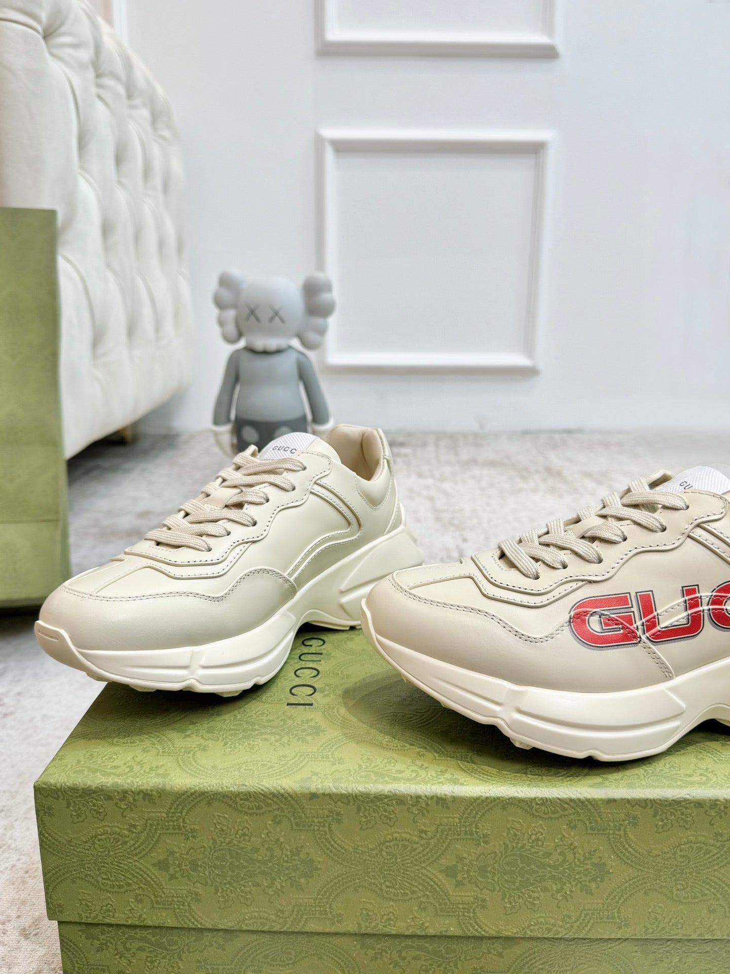 Cream Gucci unisex lace-up sneakers with red GUCCI side logo and thick sole.