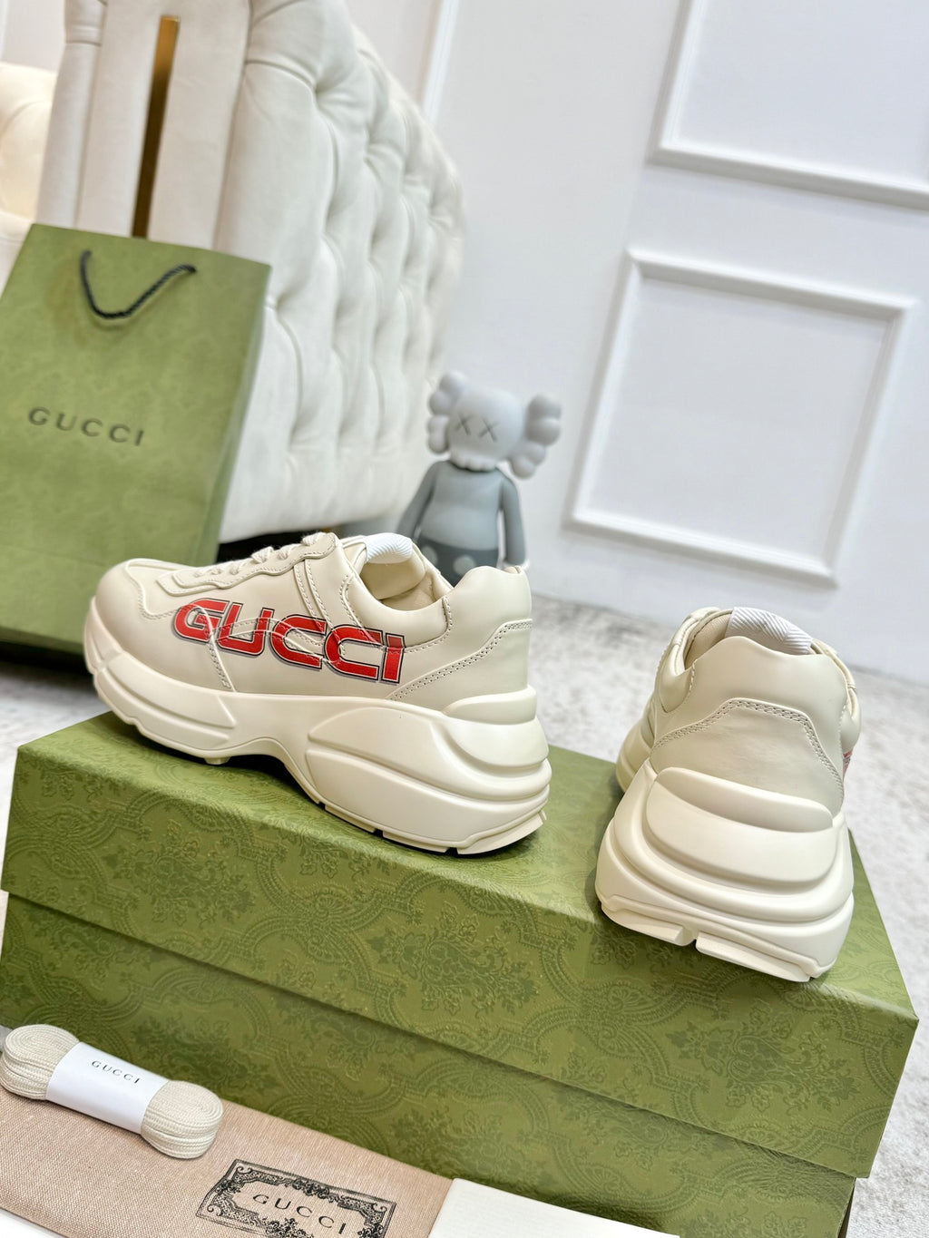 Cream Gucci unisex lace-up sneakers with red GUCCI logo, rear and side view.
