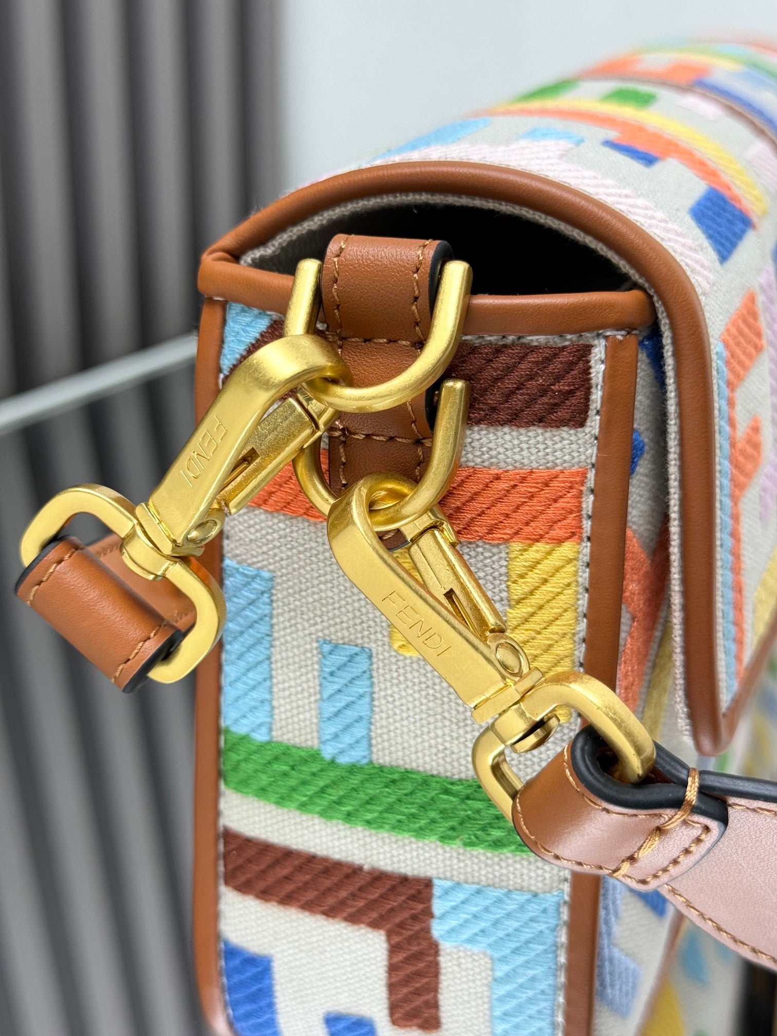 Tan leather strap with gold buckle and chain hardware on multicolor FF jacquard bag