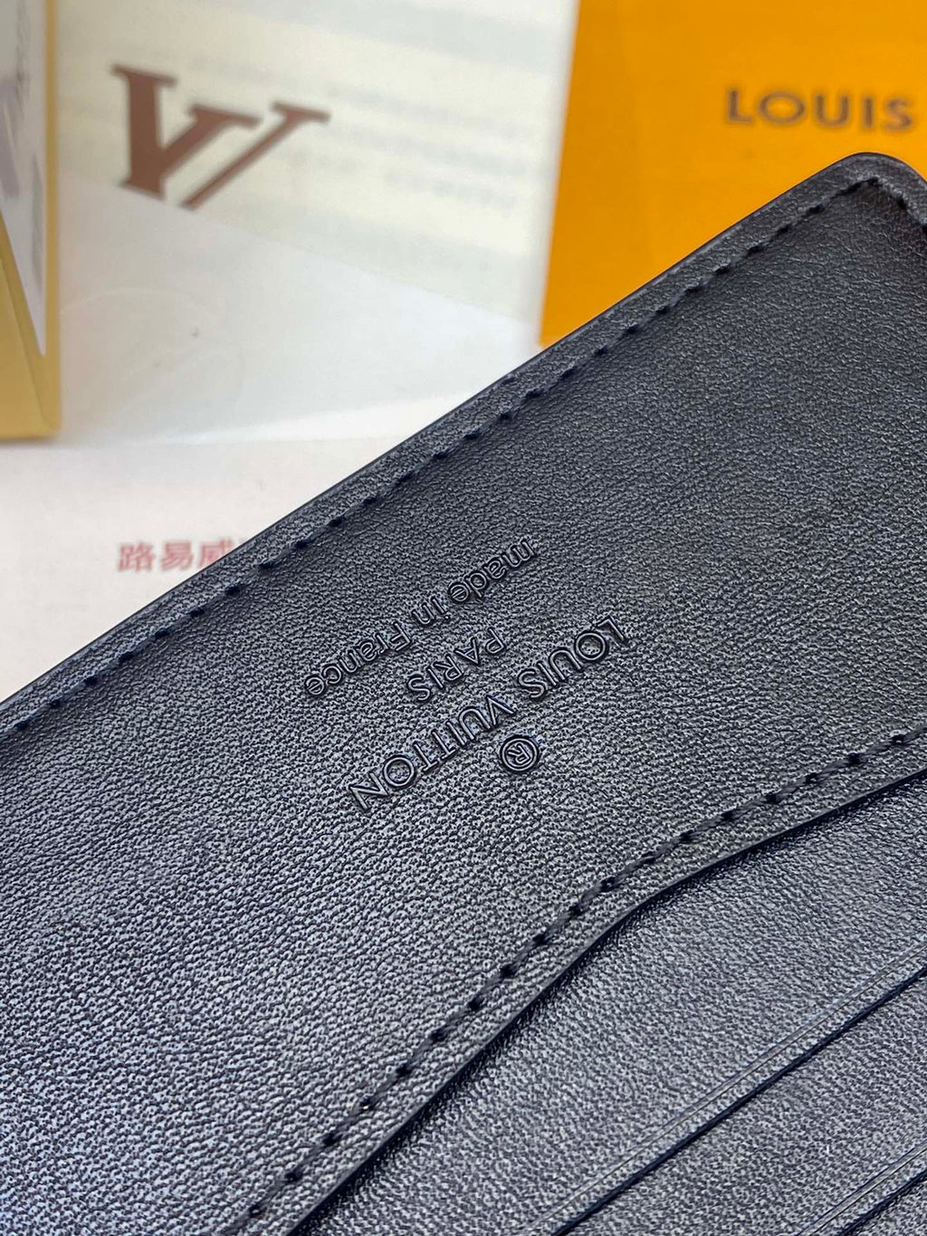 Small leather wallet close-up with embossed logo and stitched trim