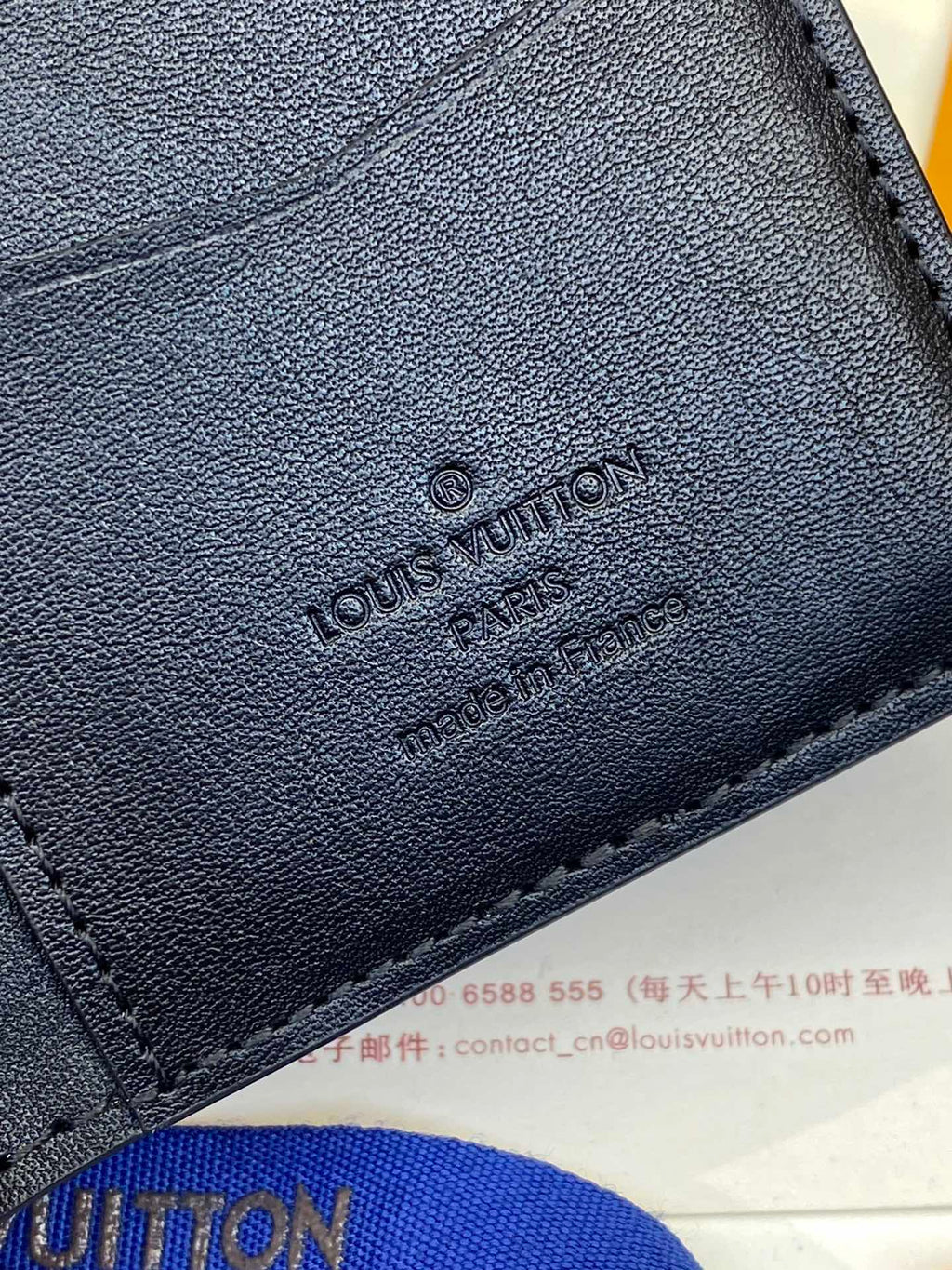 Dark blue leather wallet with embossed Louis Vuitton logo on front