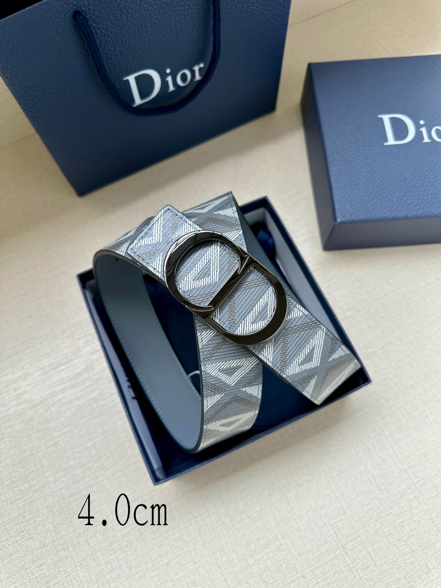 Dior belt with patterned strap and oval D buckle, showing leather keeper strap