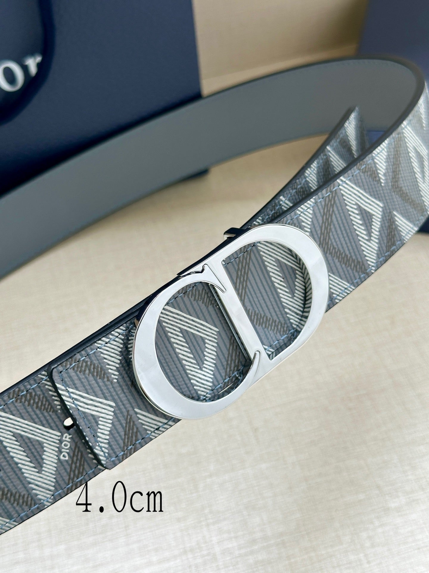 Dior belt close-up of geometric strap and oval logo buckle, metallic finish
