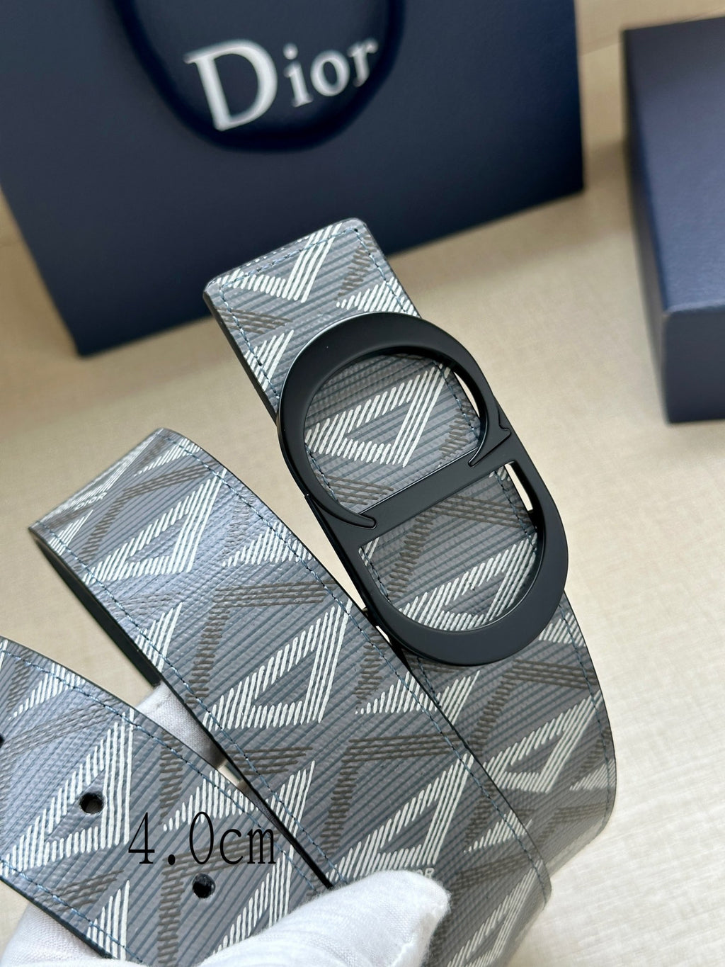 Dior belt close-up: light blue patterned strap with black buckle and eyelets