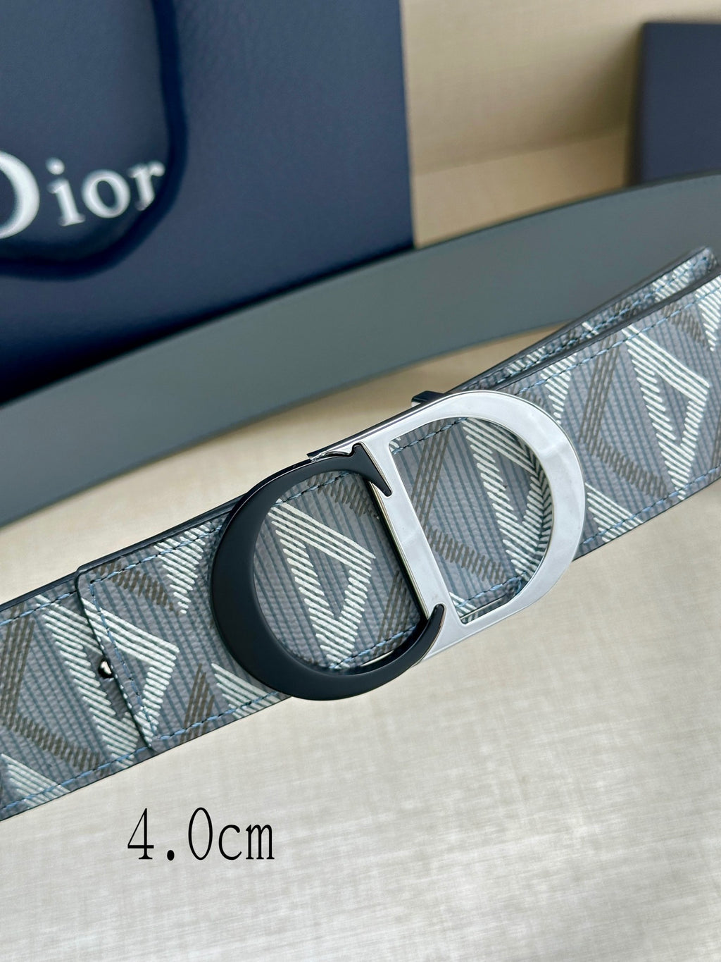 Logo-print belt close-up with silver buckle and dark insets on strap
