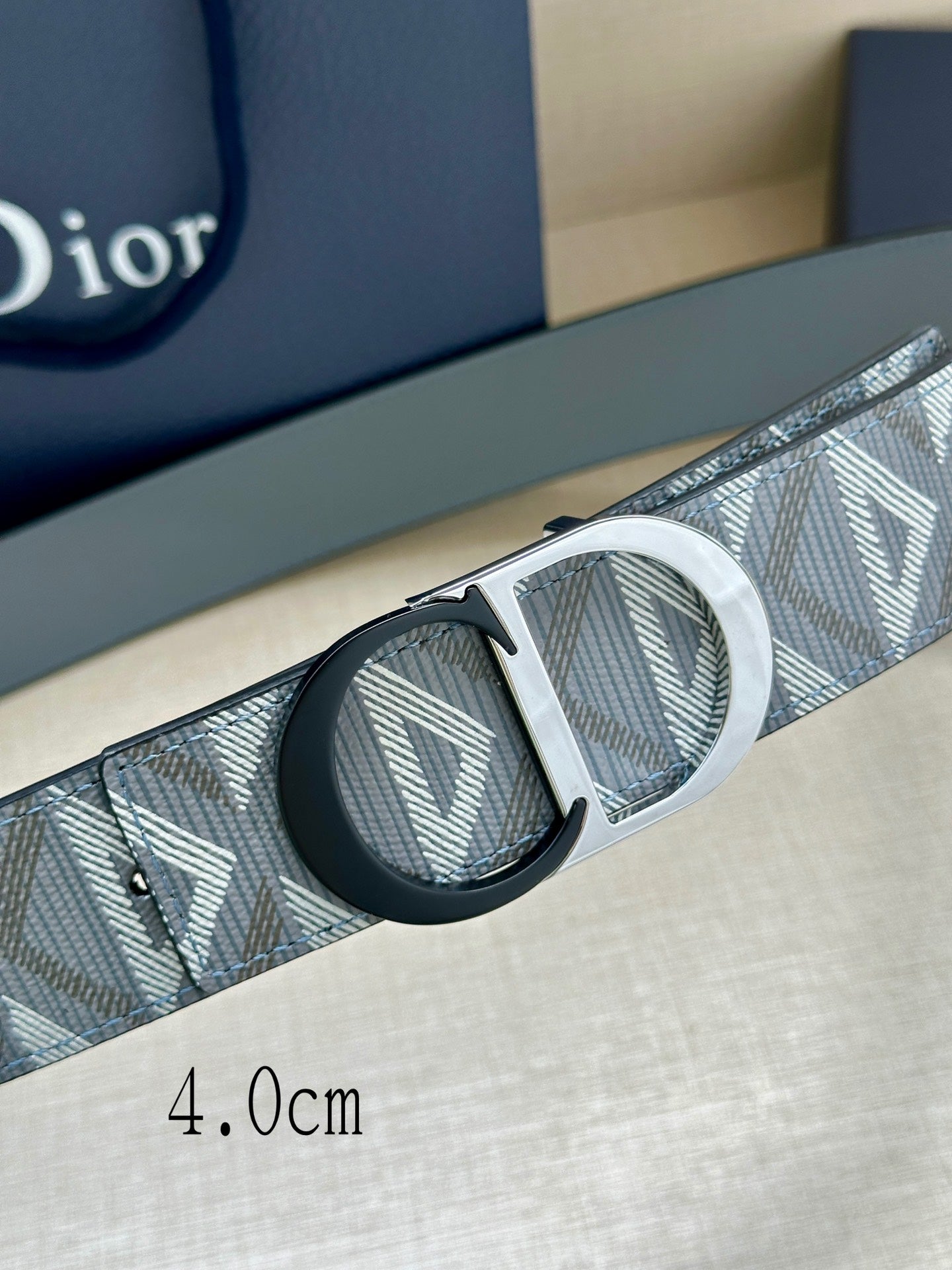 Logo-print belt close-up with silver buckle and dark insets on strap