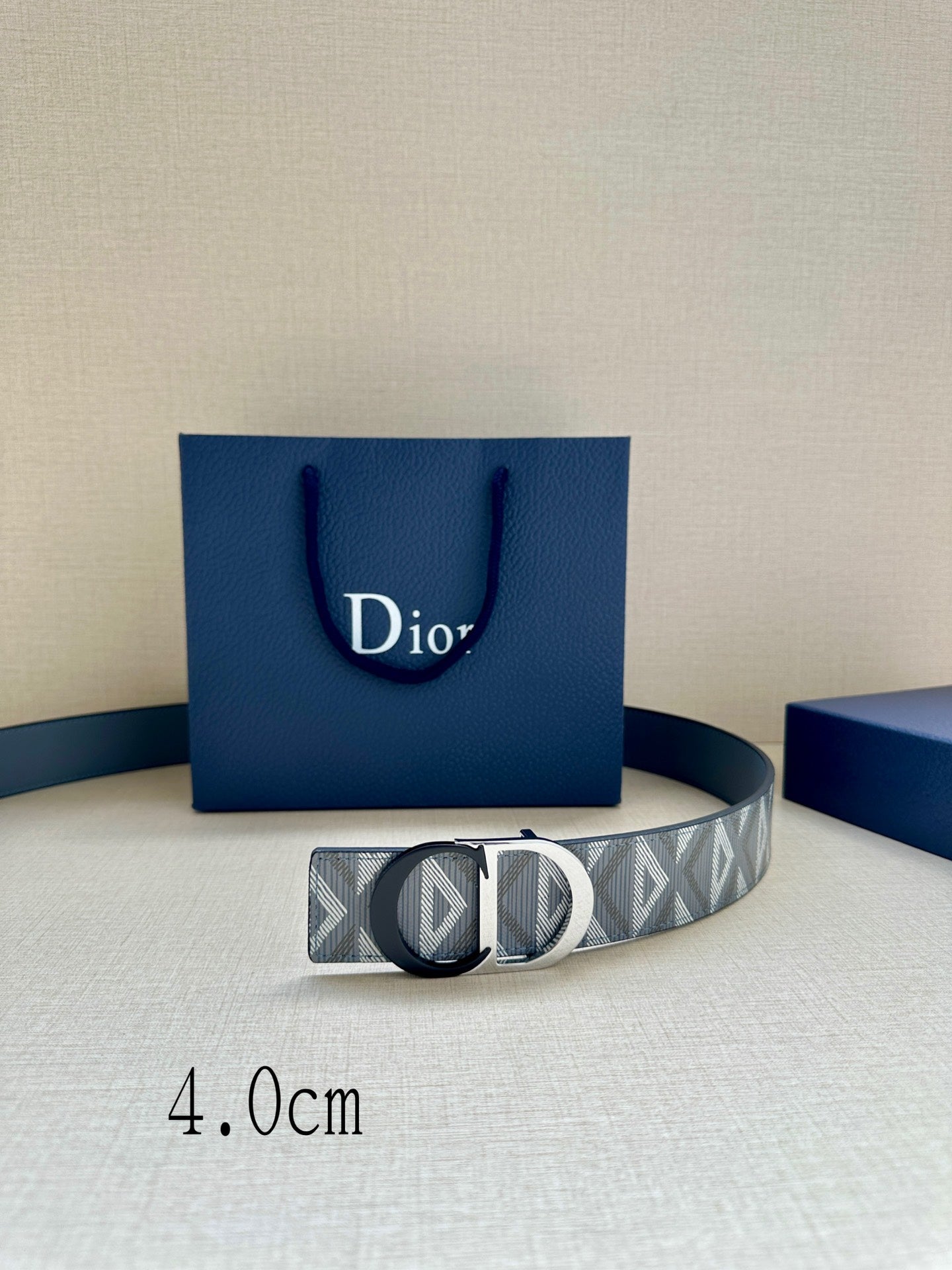 Logo-print belt with silver buckle resting on a blue display box