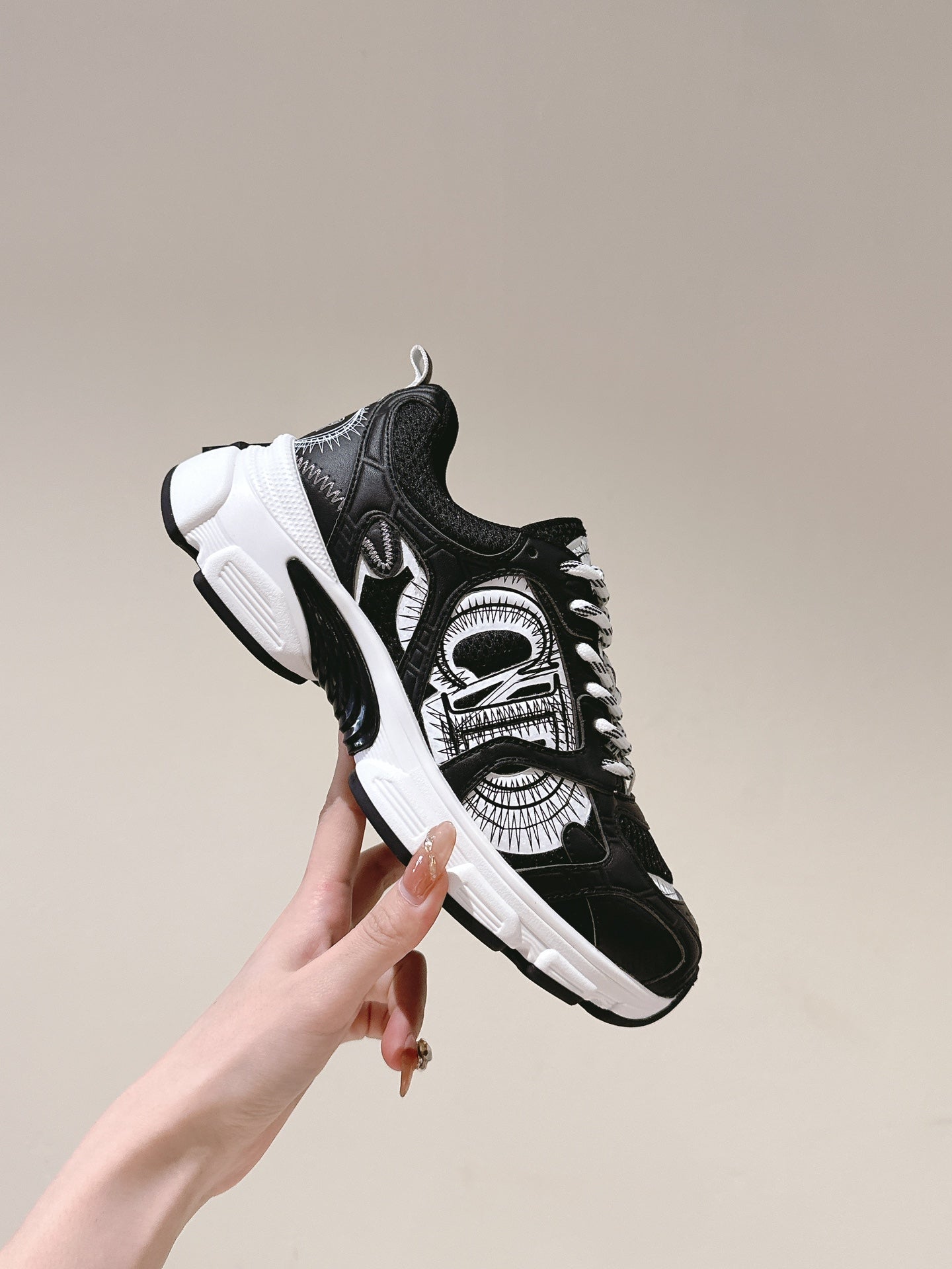 Unisex sneaker held up: black and white patterned upper and white sole