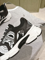 Unisex sneaker close-up: black upper with white stitching and panel art