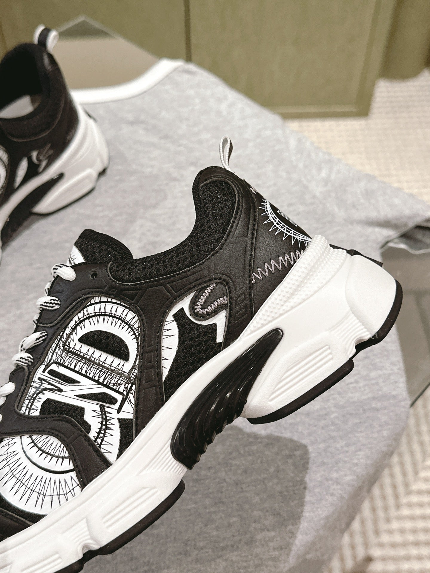 Unisex sneaker close-up: black upper with white stitching and panel art