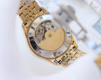Rolex wristwatch caseback view with visible inner movement, gold-tone link bracelet