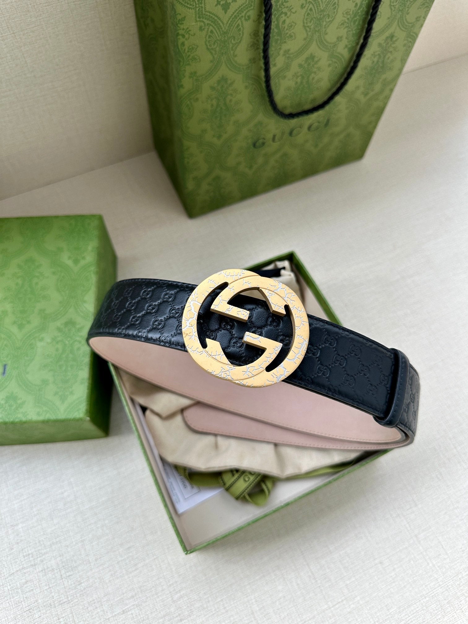 Dark blue leather belt with silver logo buckle over folded packaging materials