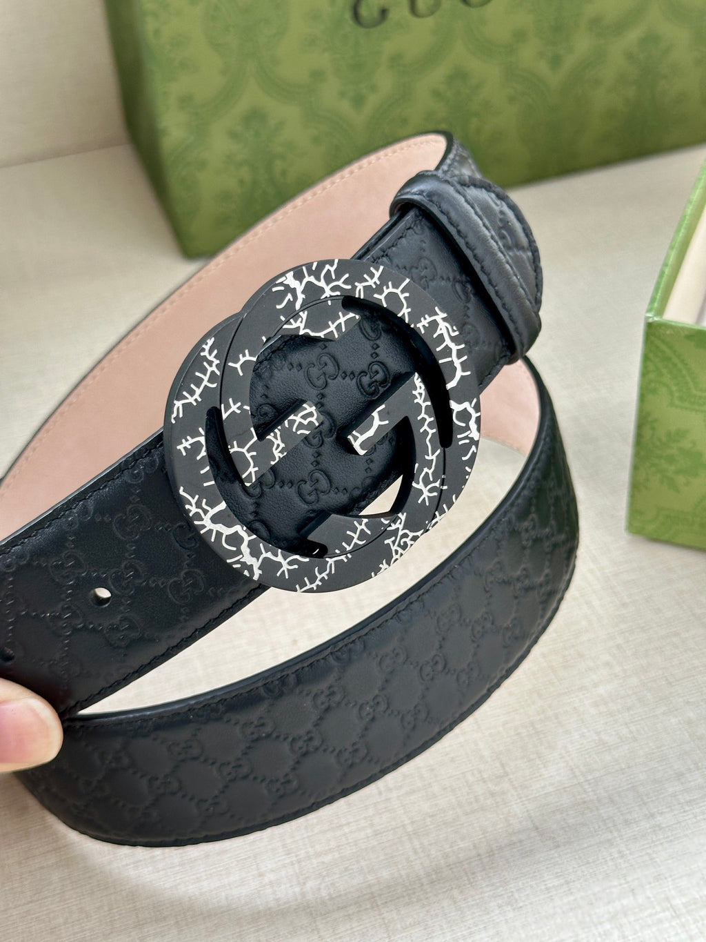 Dark blue leather belt with round black-and-white logo buckle close-up