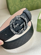 Dark blue leather belt with round black-and-white logo buckle close-up