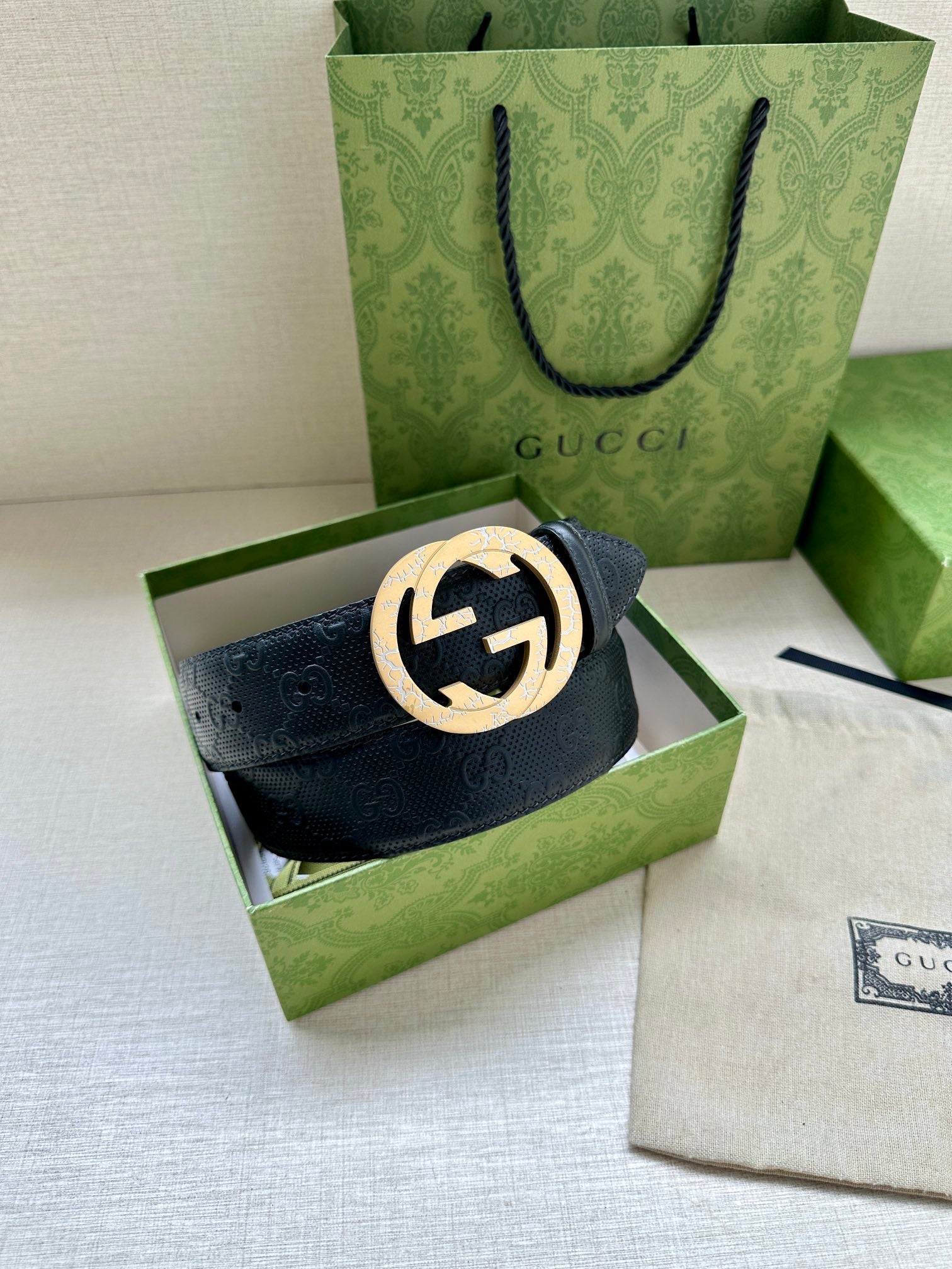 Dark blue leather belt with large gold logo buckle on display box