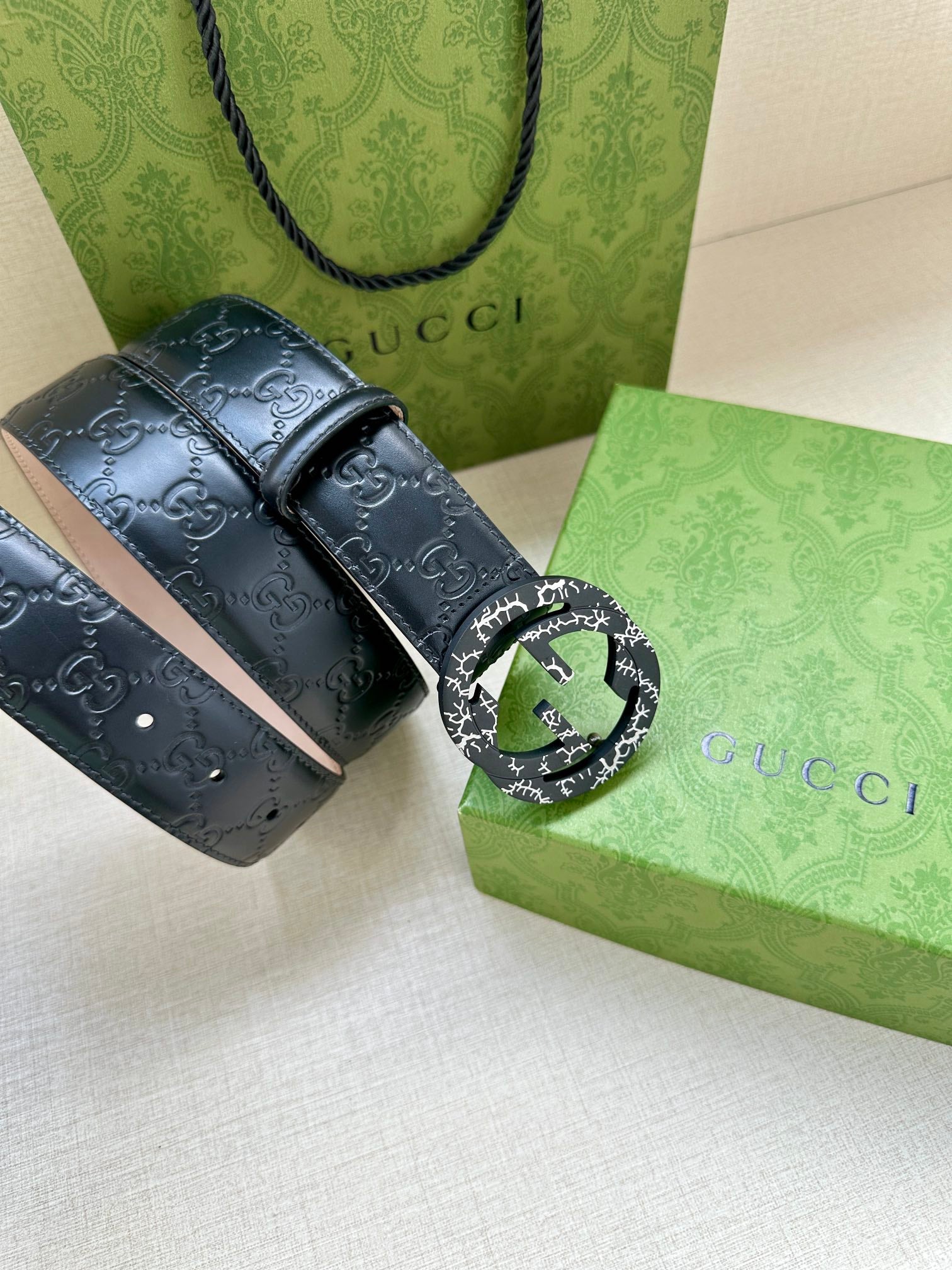 Gucci belt close-up: dark navy GG patterned leather with silver-tone buckle detail
