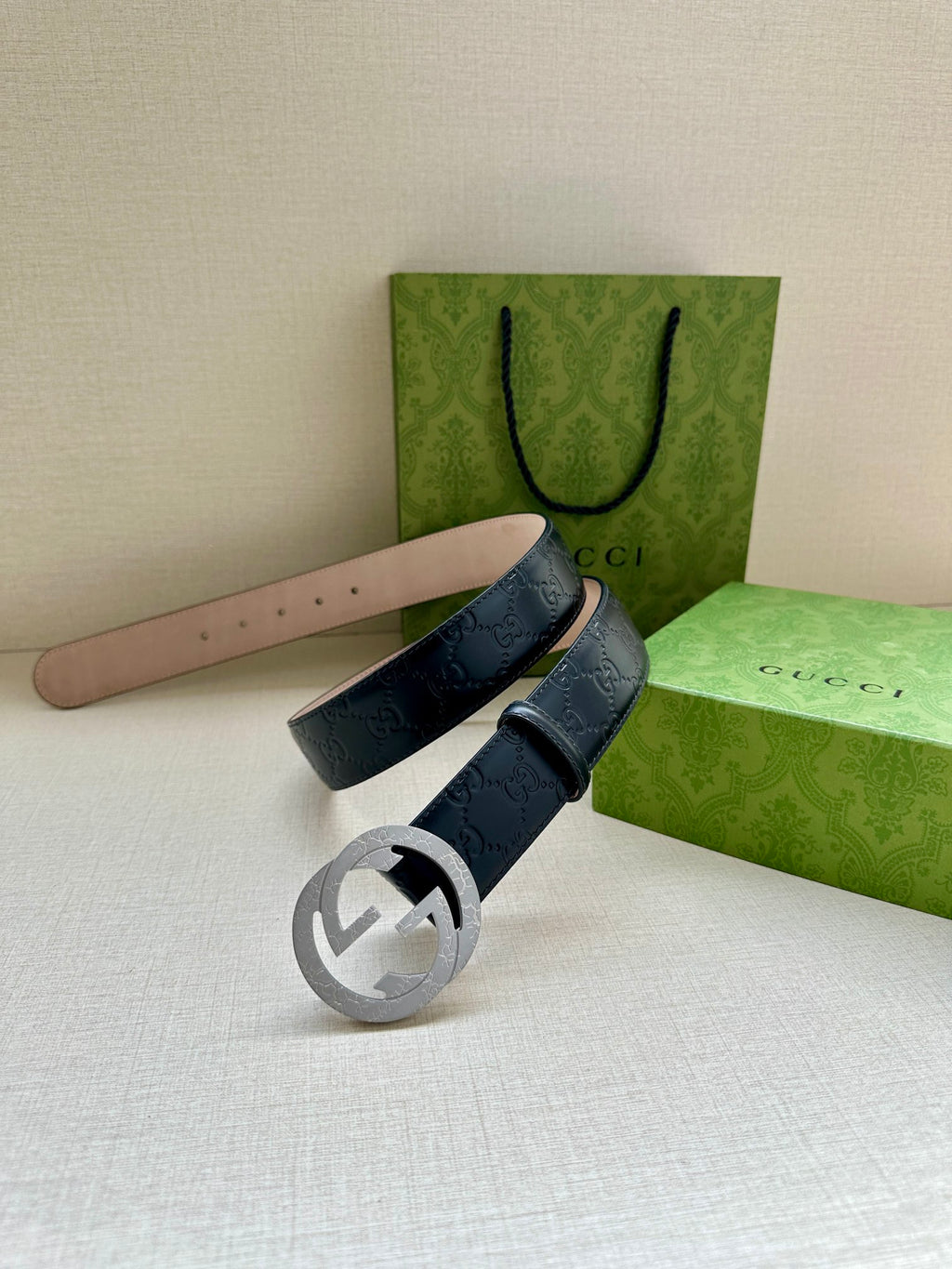 Gucci belt laid flat: dark navy GG strap with silver-tone double-G buckle