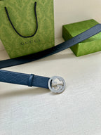 Gucci belt laid flat in dark blue leather with embossed logo and circular GG buckle