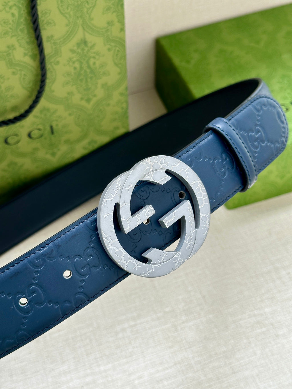 Gucci belt close-up of dark blue leather with embossed logo and silver-tone GG buckle