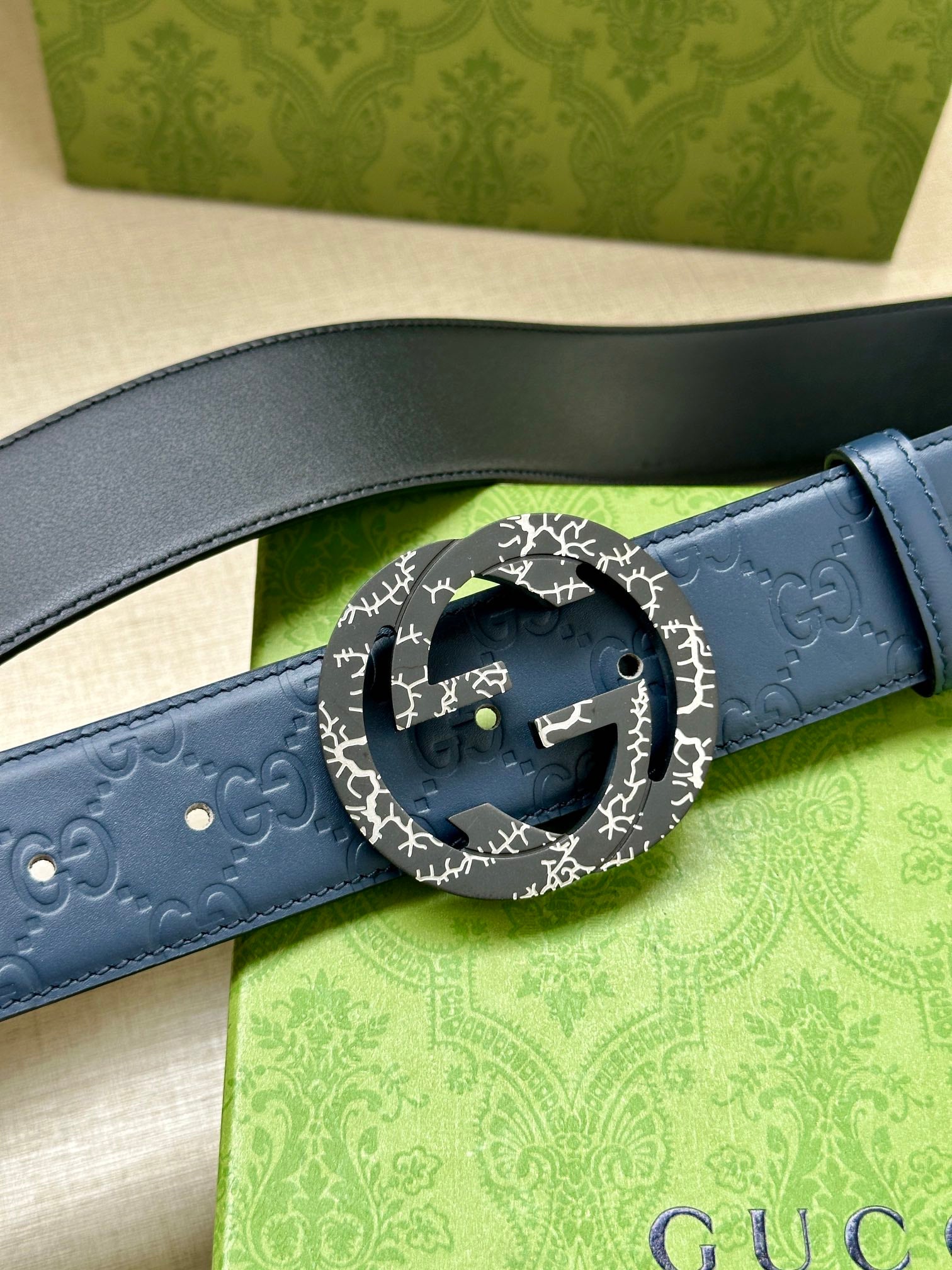 Gucci belt close-up: dark blue leather strap with patterned GG buckle ring