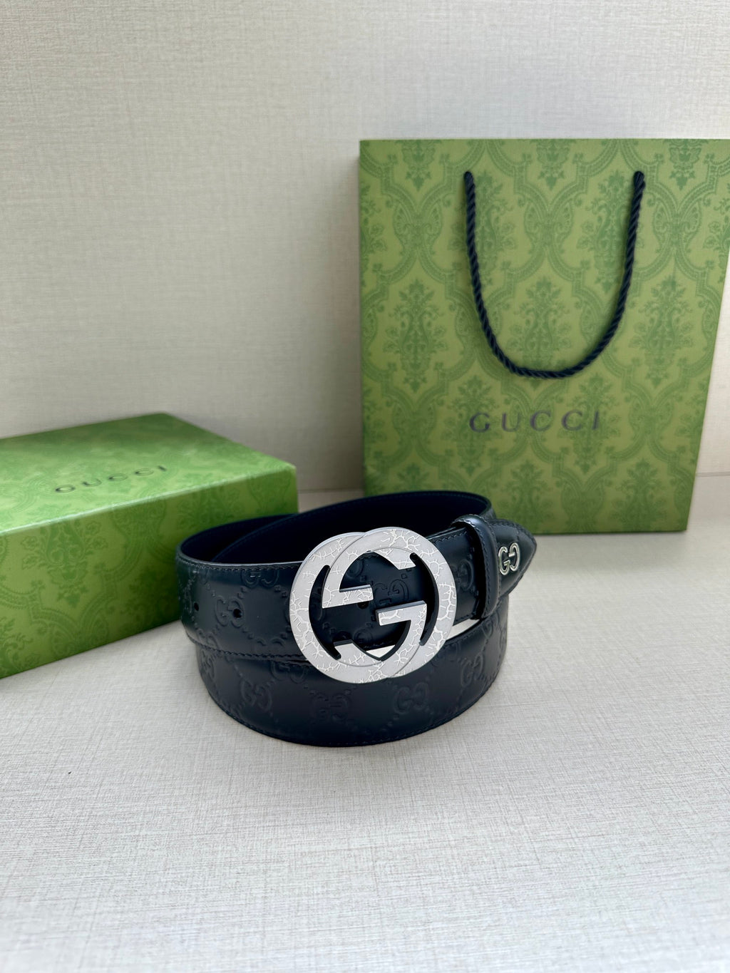 Gucci belt with dark blue leather and embossed pattern, featuring a silver-toned logo buckle