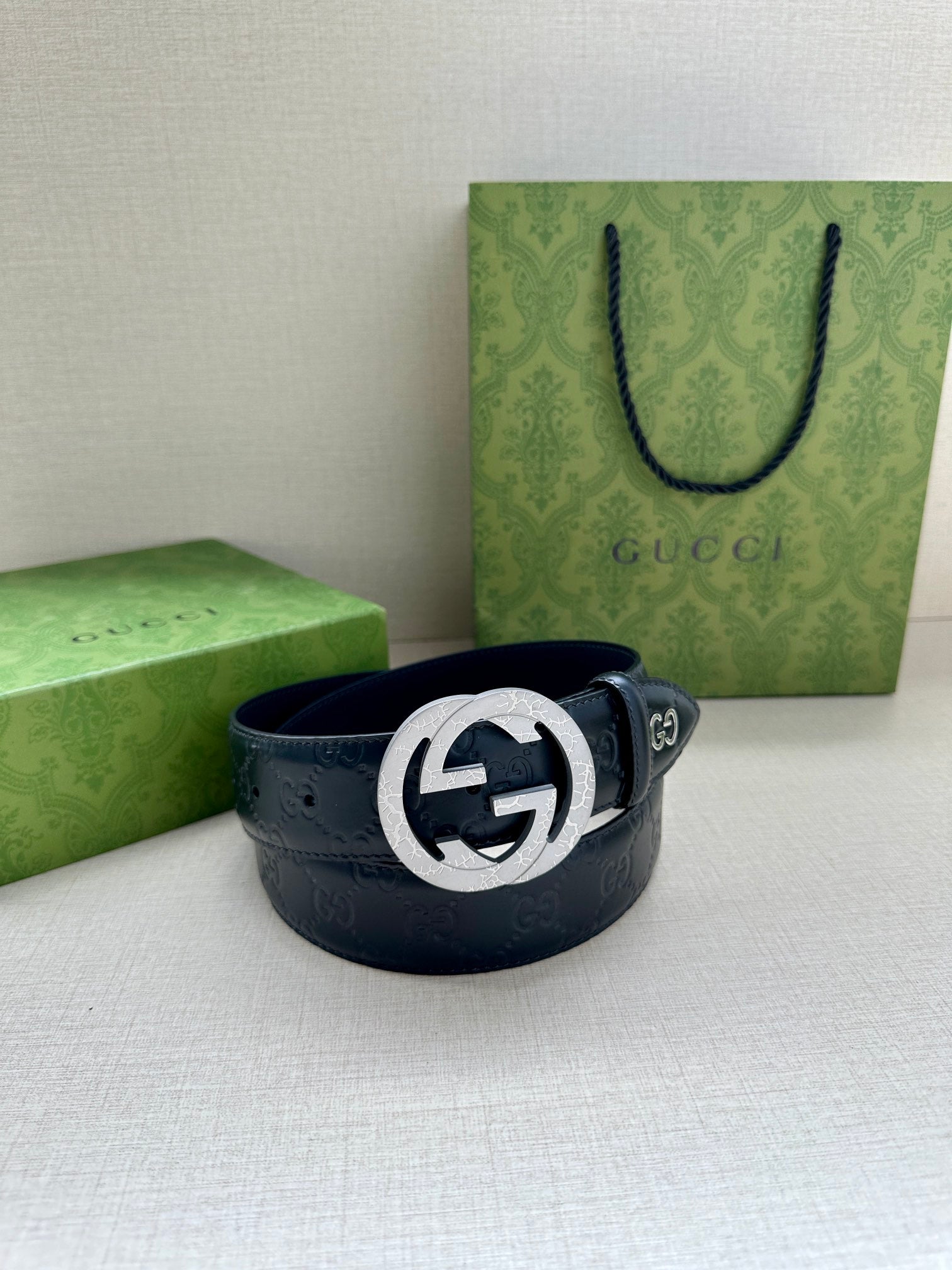Gucci belt with dark blue leather and embossed pattern, featuring a silver-toned logo buckle
