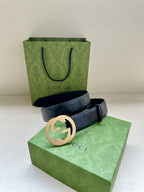 Gucci belt with dark blue embossed leather and a round gold-toned buckle in front view