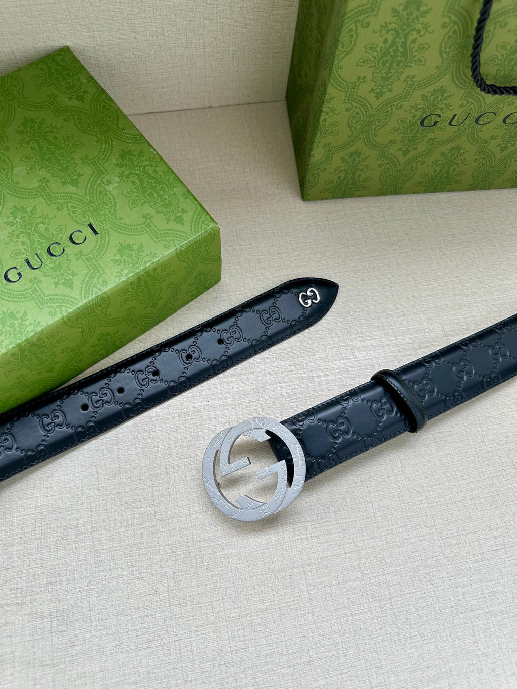 Gucci belt laid flat, dark blue embossed leather with a silver-toned round buckle