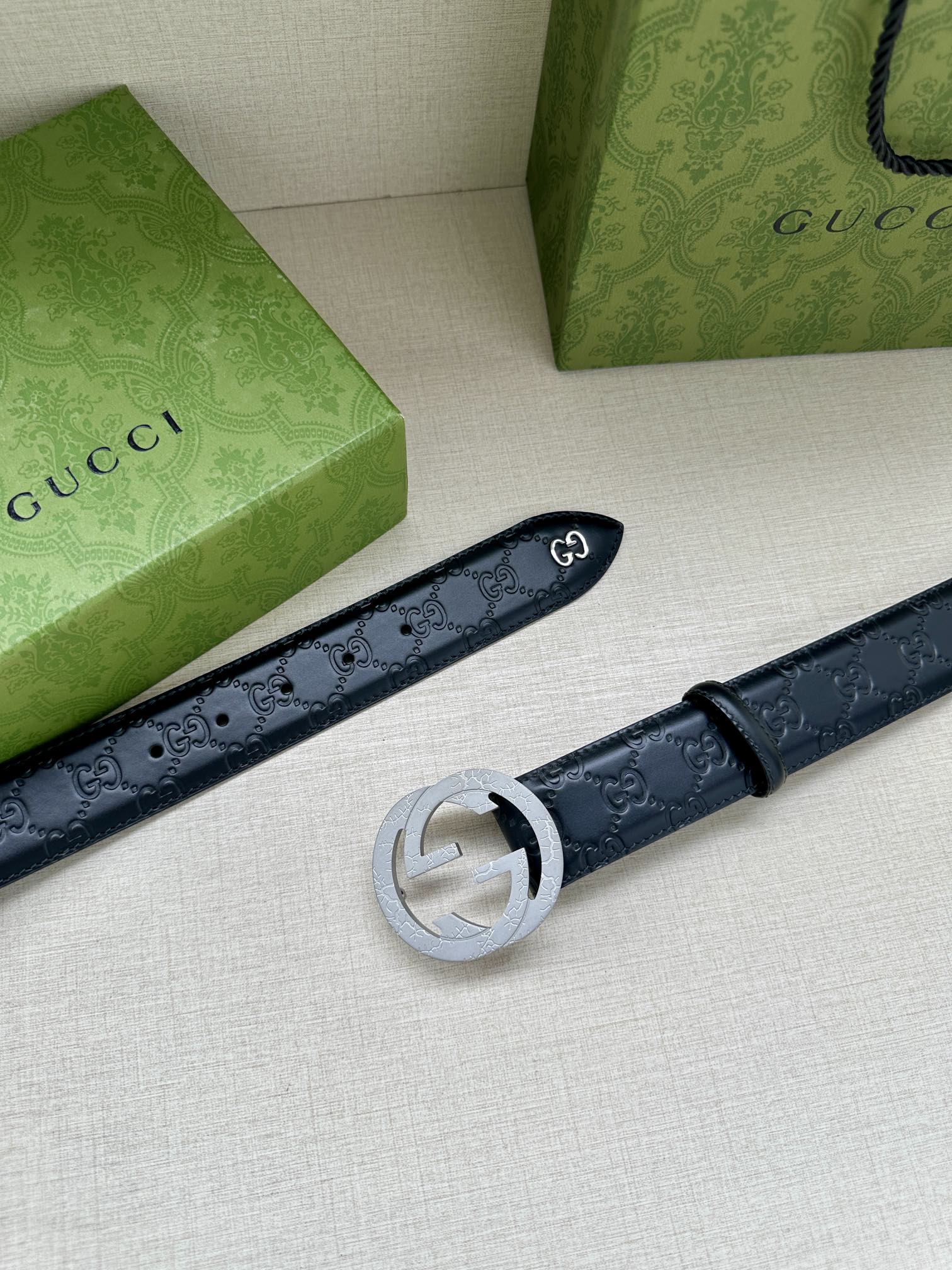 Gucci belt laid flat, dark blue embossed leather with a silver-toned round buckle