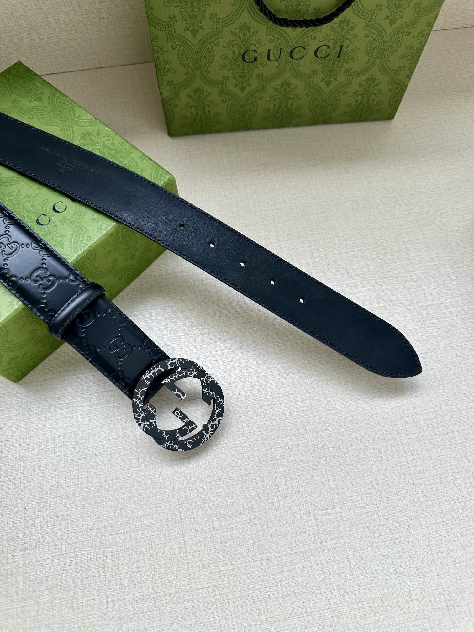 Gucci belt strap close-up, dark blue embossed leather with a silver logo buckle