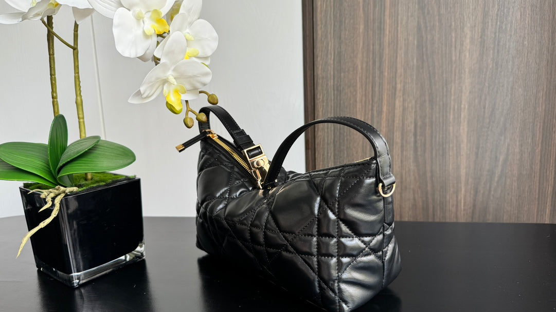 Quilted black handbag with curved handle and gold-tone clasp hardware