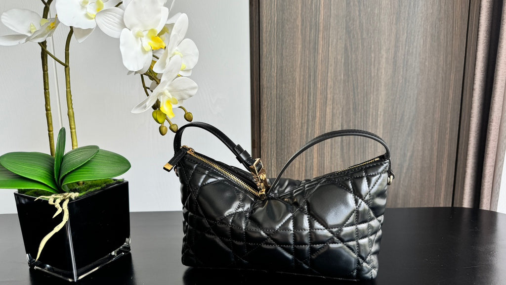Quilted black handbag with top handle and gold-tone hardware, side angle view