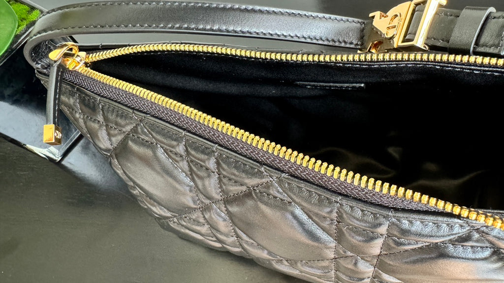Black quilted handbag interior close-up with gold zipper and stitched lining