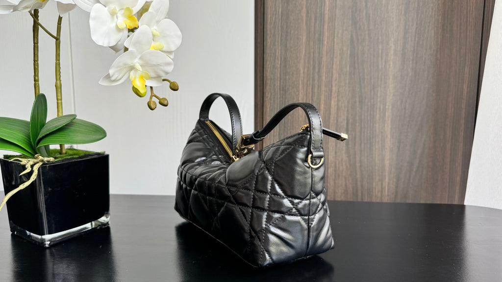 Quilted black handbag with top handles and gold-tone hardware, side view