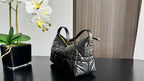 Quilted black handbag with top handles and gold-tone hardware, side view