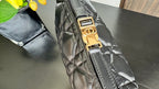 Black quilted handbag strap hardware with gold-tone buckle and stitched seam