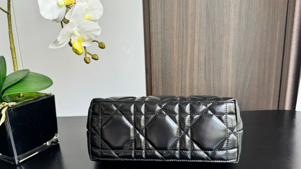 Quilted black handbag front view with two top handles and gold-tone accents