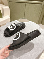 Black slide sandals with white GG logo straps, angled pair view